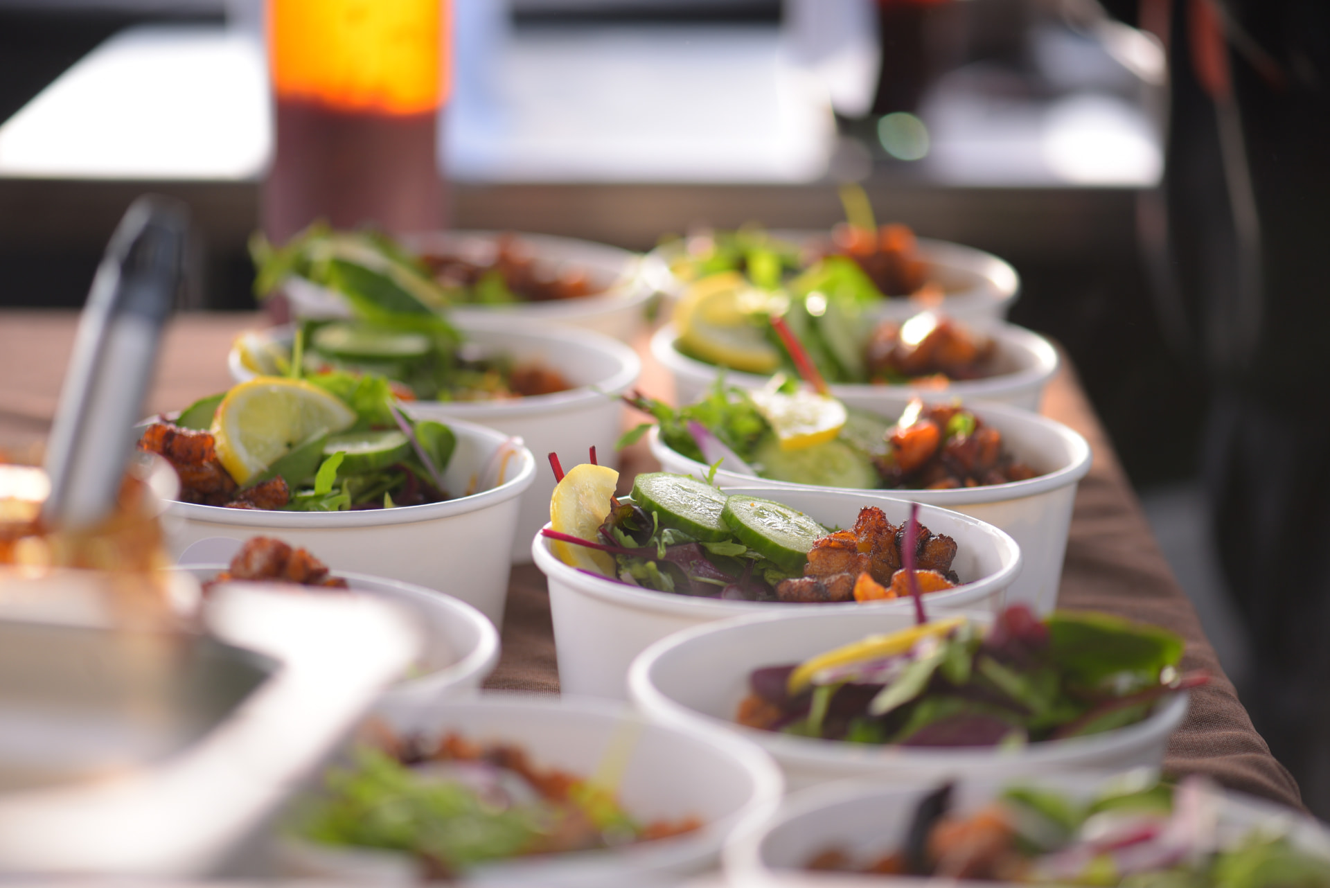 Fresh salad and grill cups lined up at an outdoor event